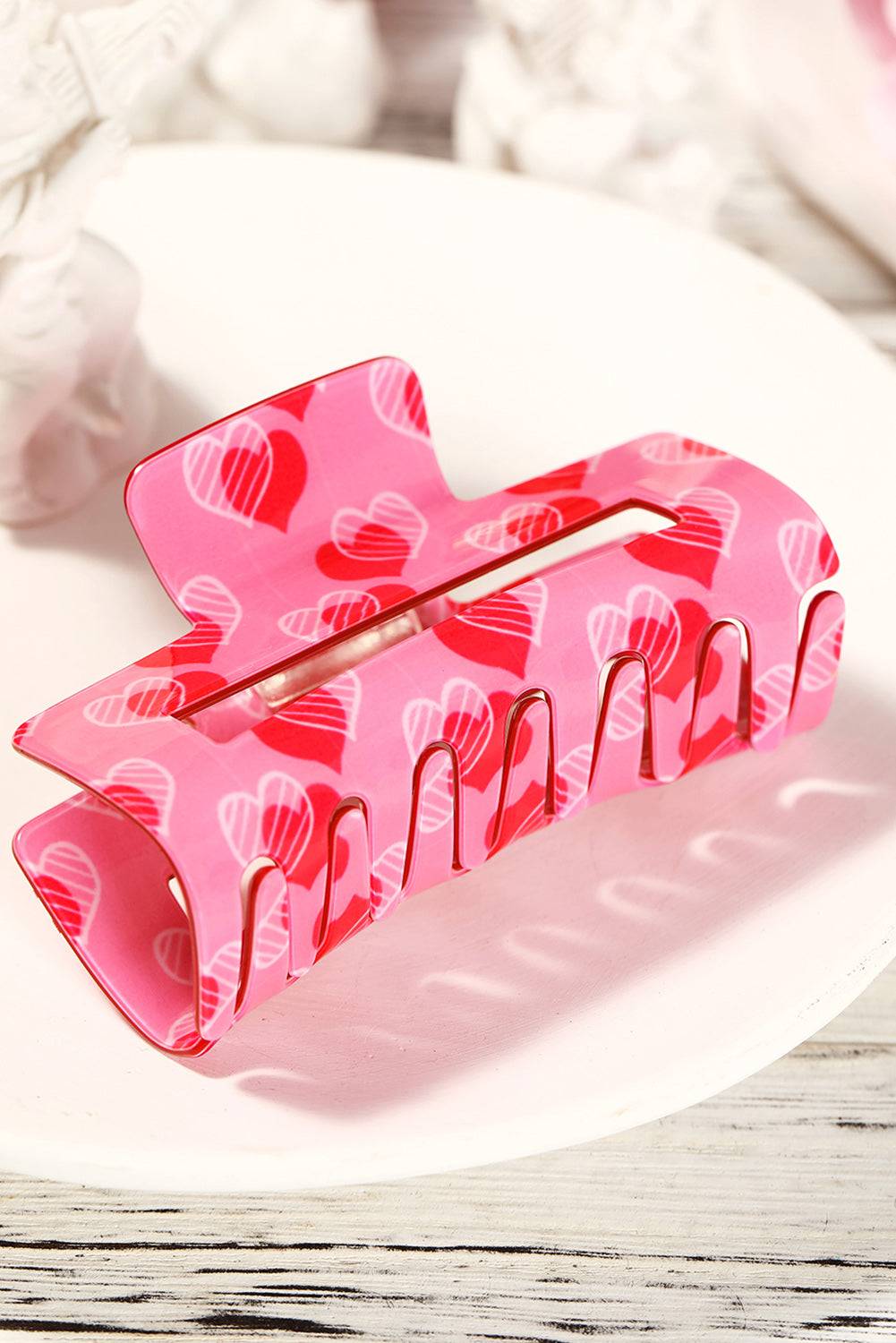 Pink hair clip with heart pattern on a white surface