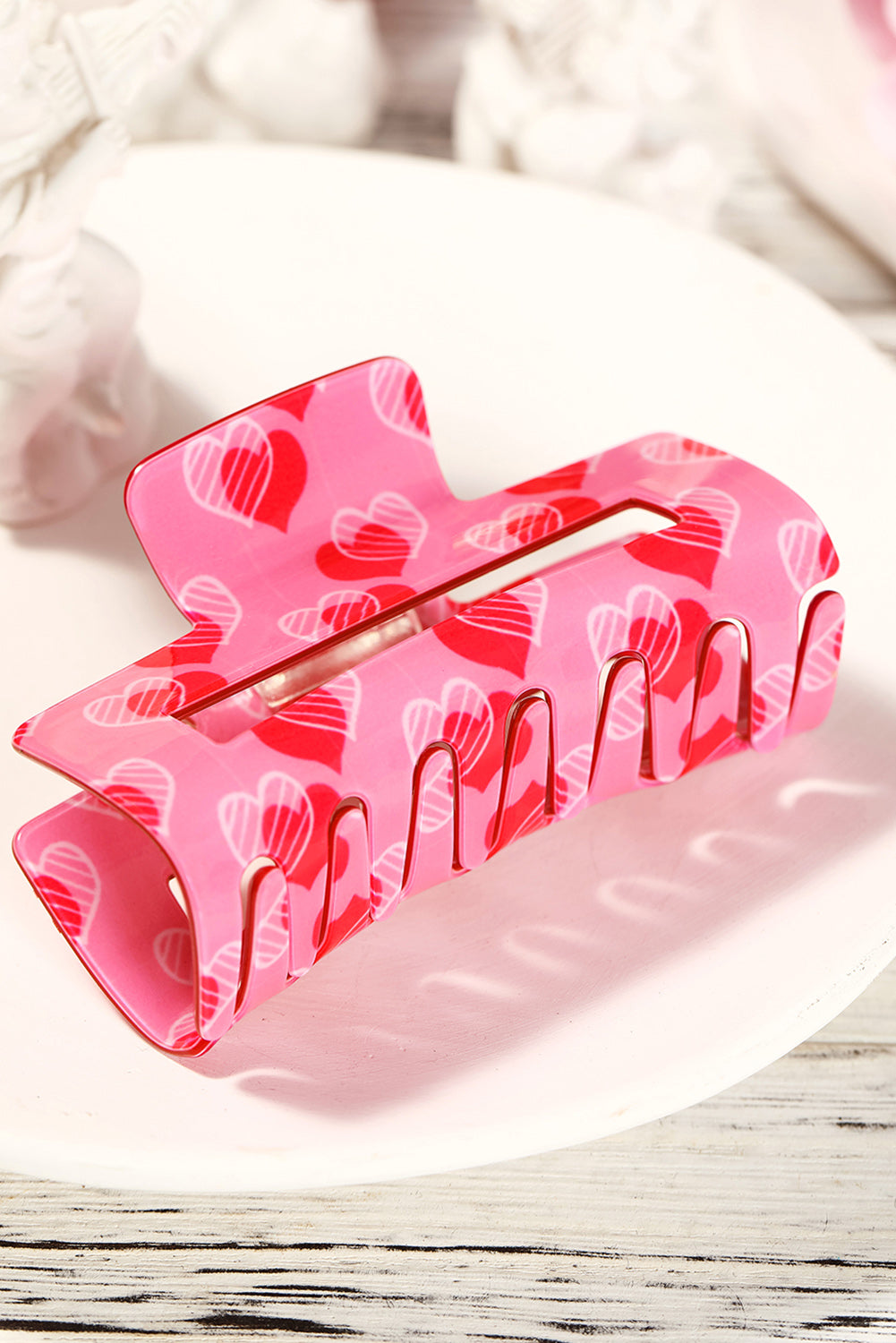 Pink hair clip with heart pattern on a white surface