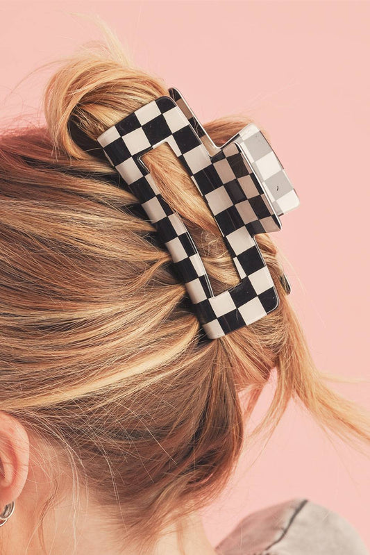 Checkered hair clip in blonde hair against a pink background