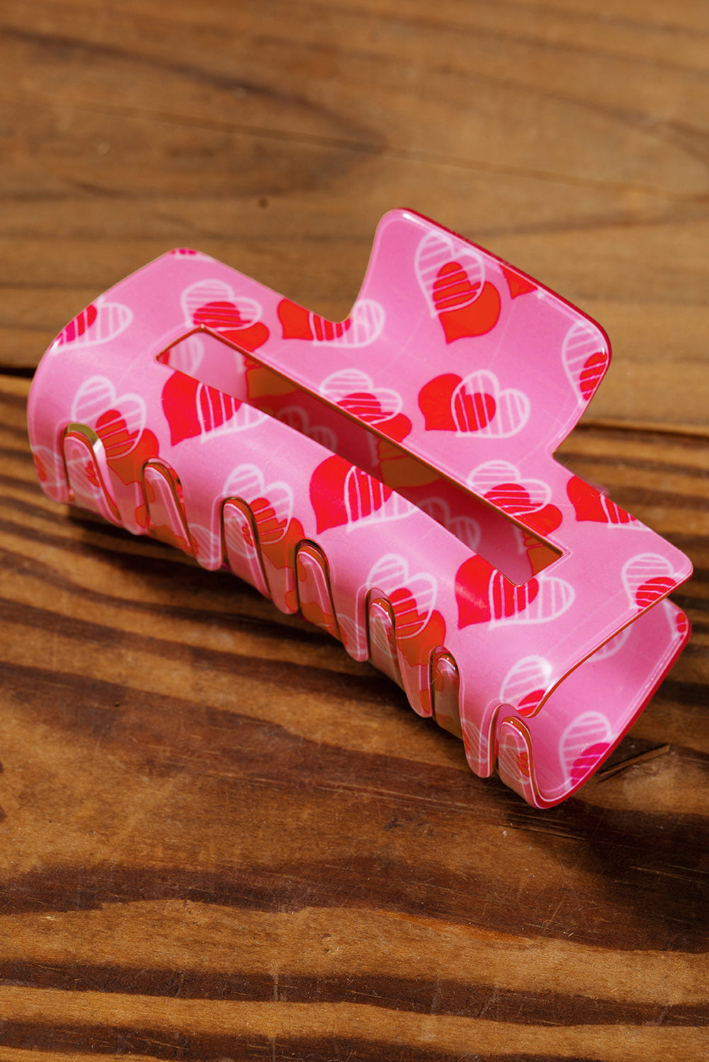 Pink hair clip with heart pattern on a wooden surface