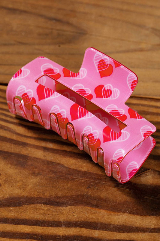 Pink hair clip with heart pattern on a wooden surface