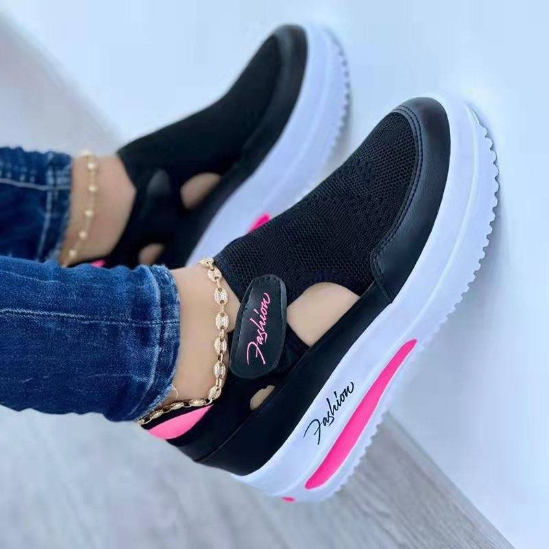Black slip-on shoes with pink accents worn by a person on a light background