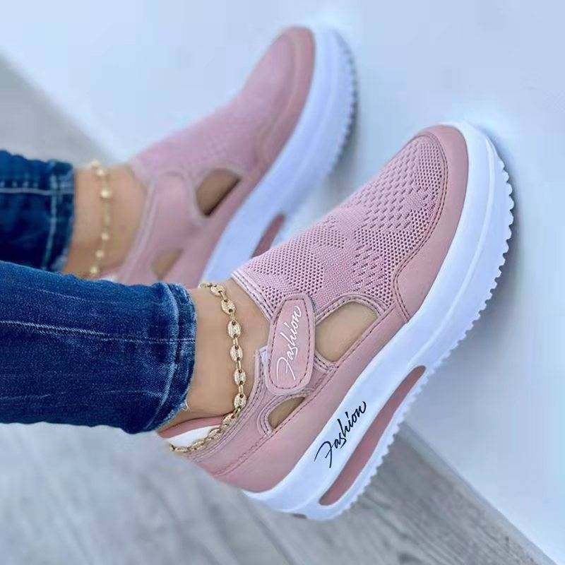 Pink sneakers with white soles worn by a person in jeans, on a light background.