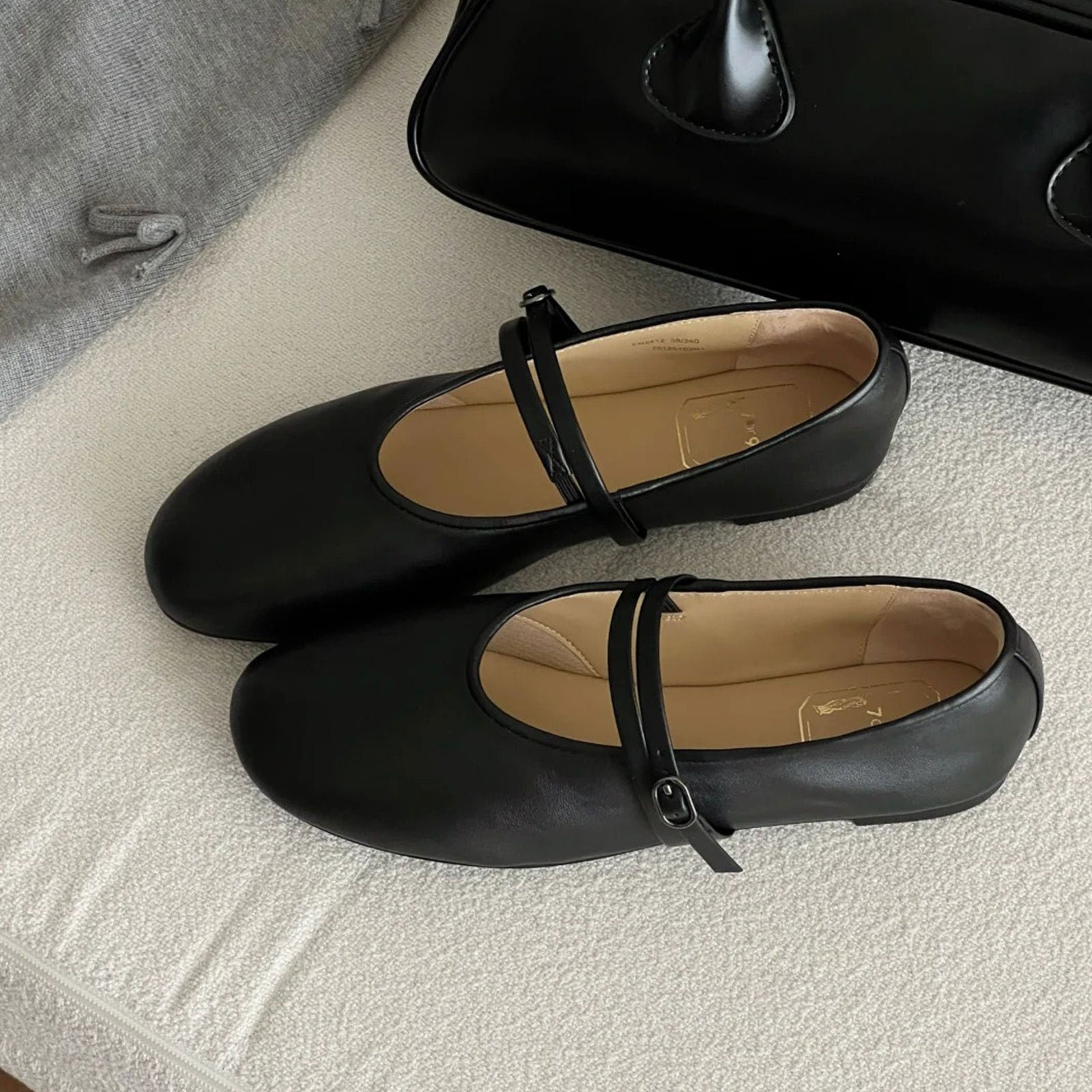 Black shoes with a strap on a textured surface
