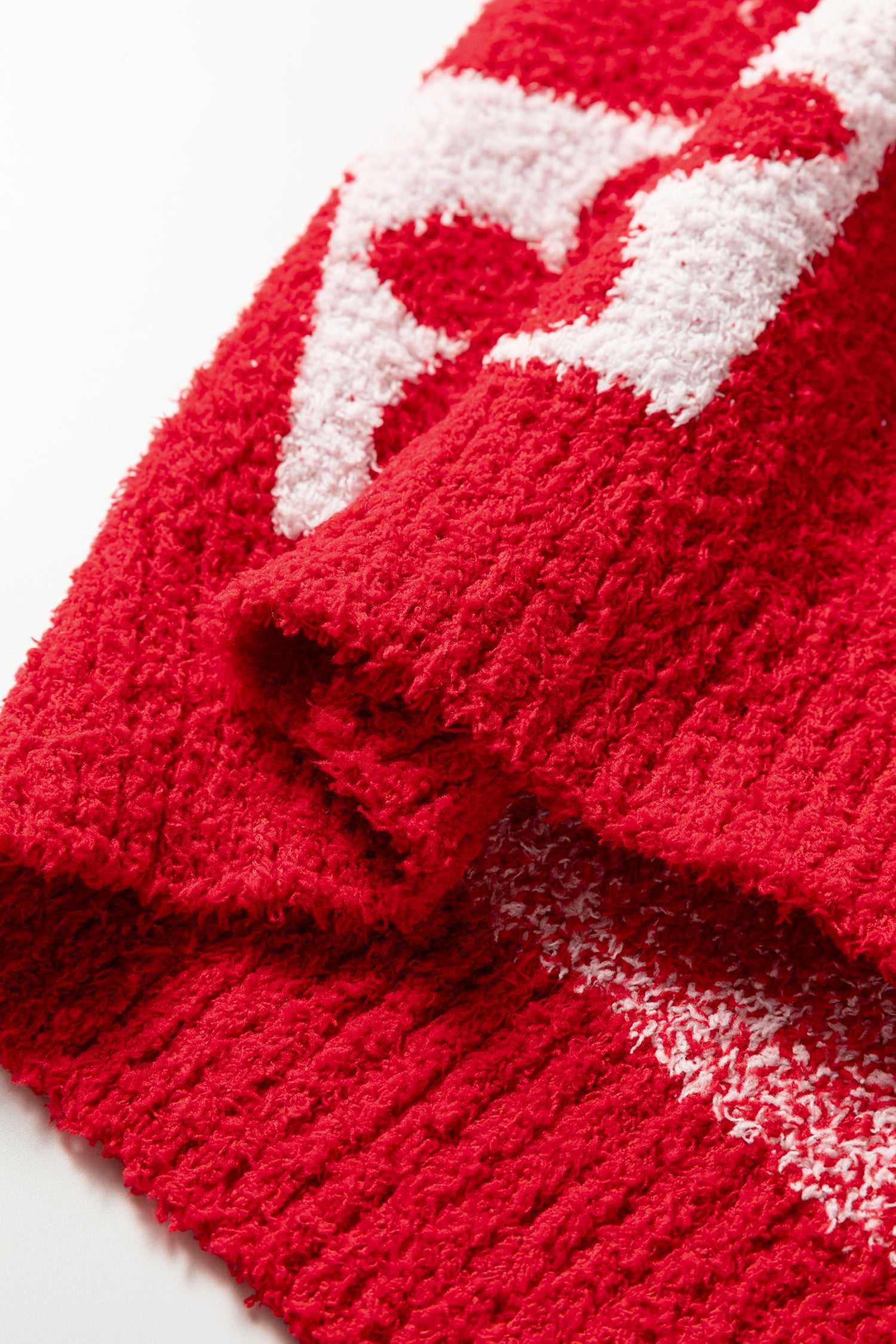 Close-up of a red knitted item with white patterns on a white background