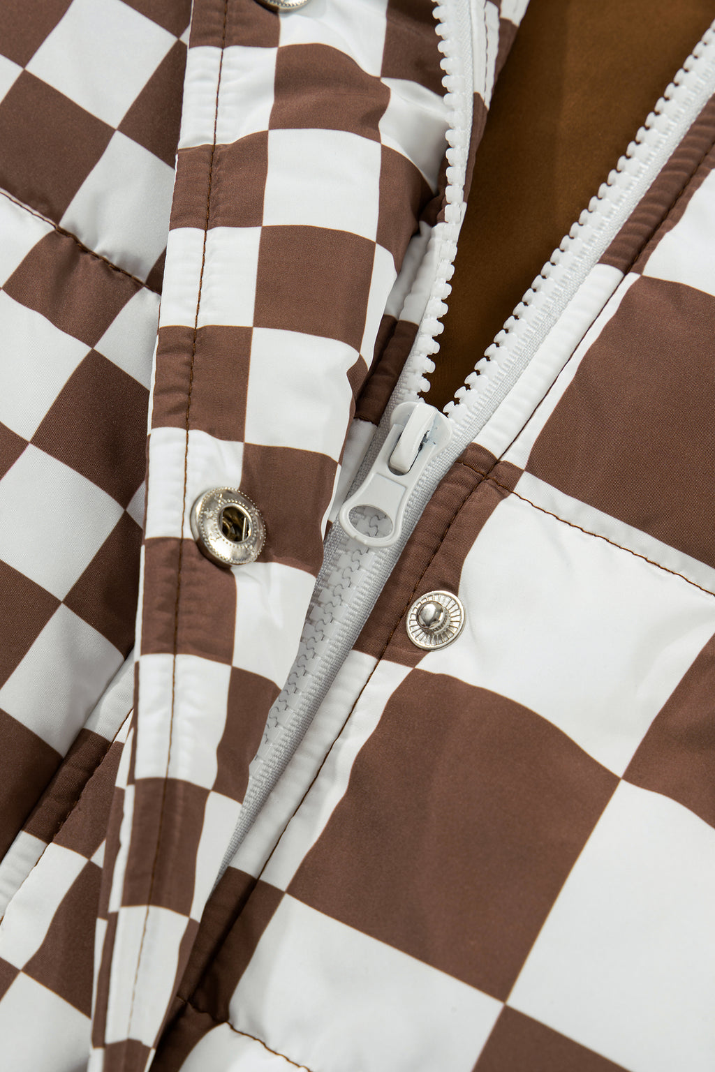 Close-up of a brown and white checkered jacket with a zipper.