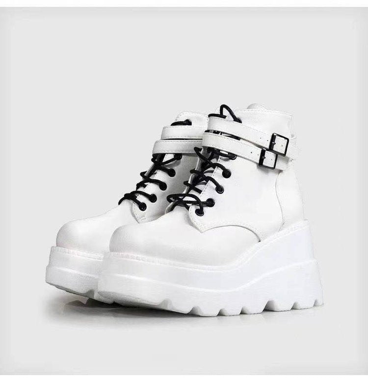 White platform boots with black laces on a light gray background