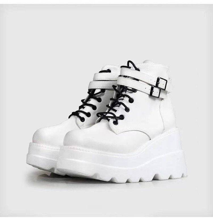 White platform boots with black laces on a light gray background