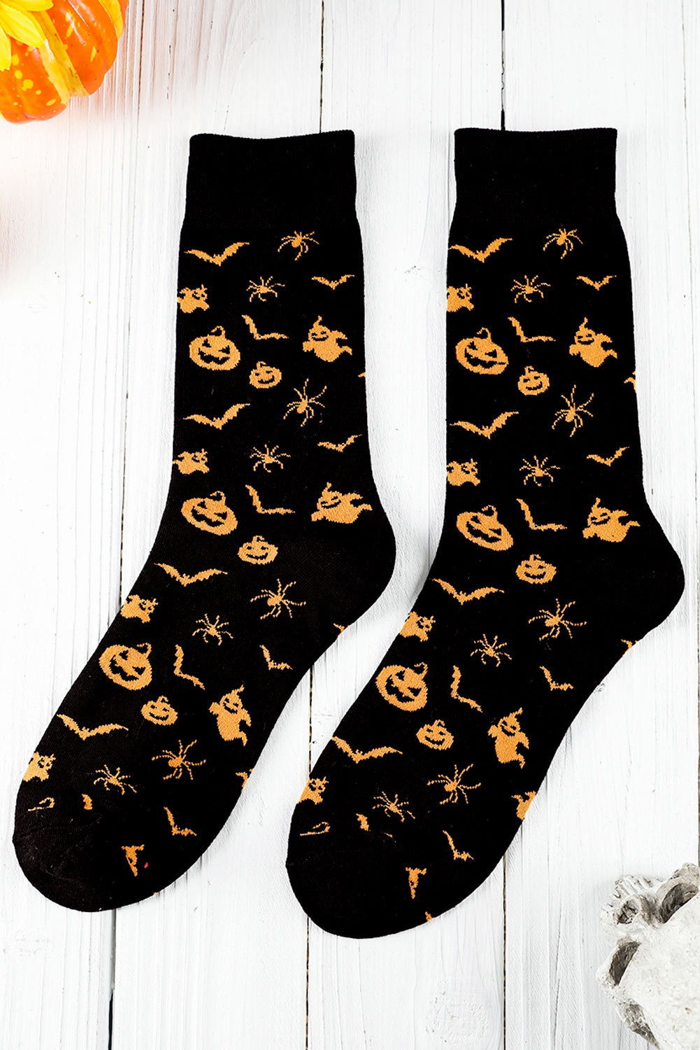 Black socks with Halloween-themed yellow patterns on a white wooden surface.