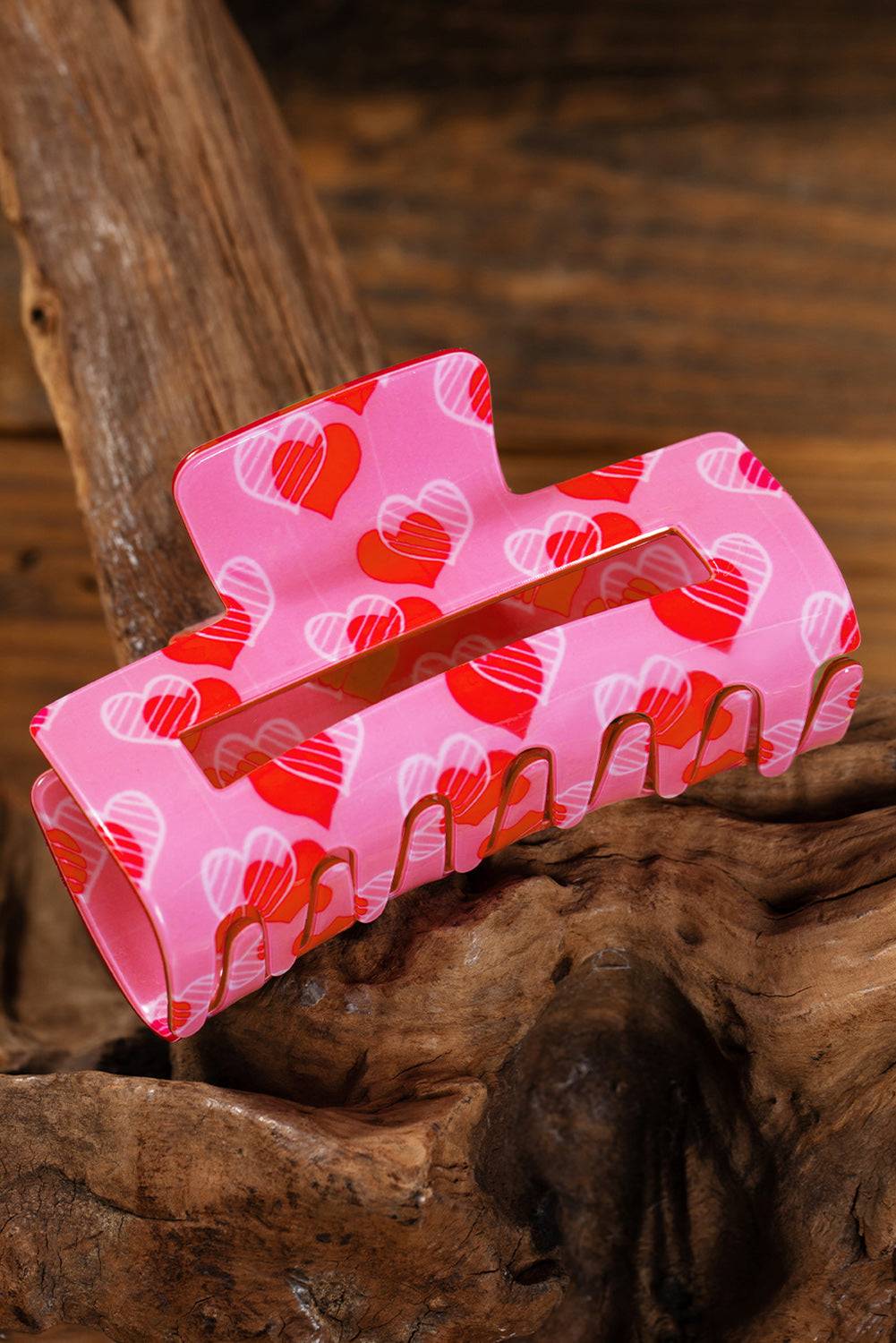 Pink hair clip with heart pattern on a wooden surface