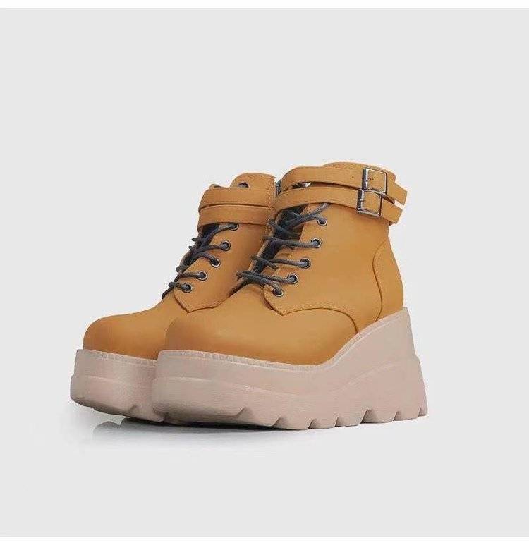 Pair of mustard yellow platform boots on a light gray background