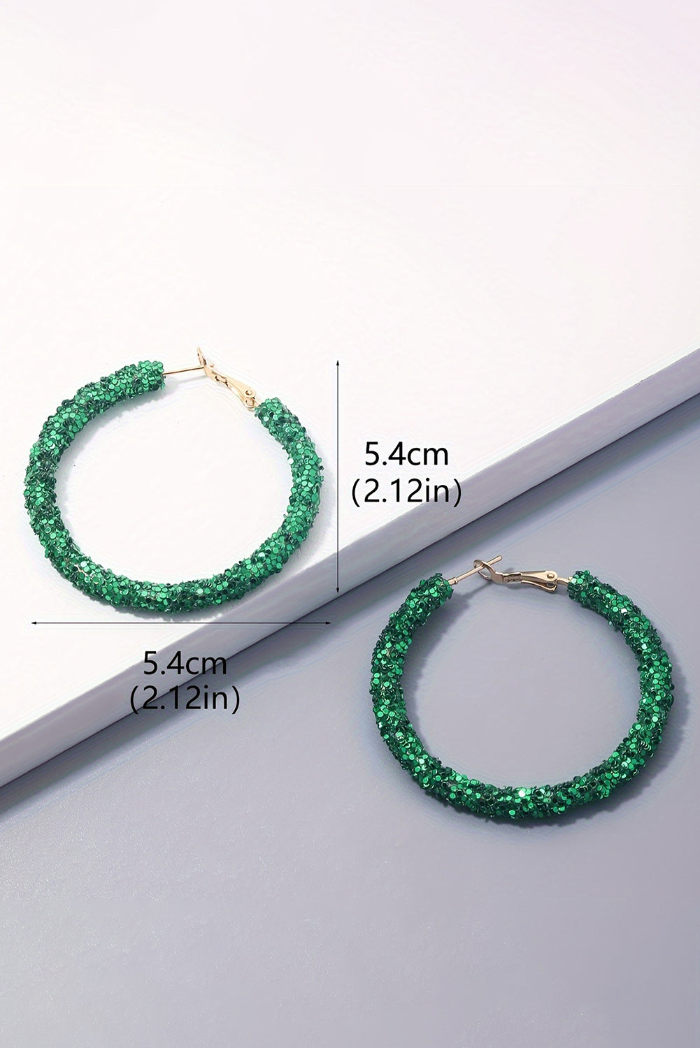 Green hoop earrings with measurements on a light gray background