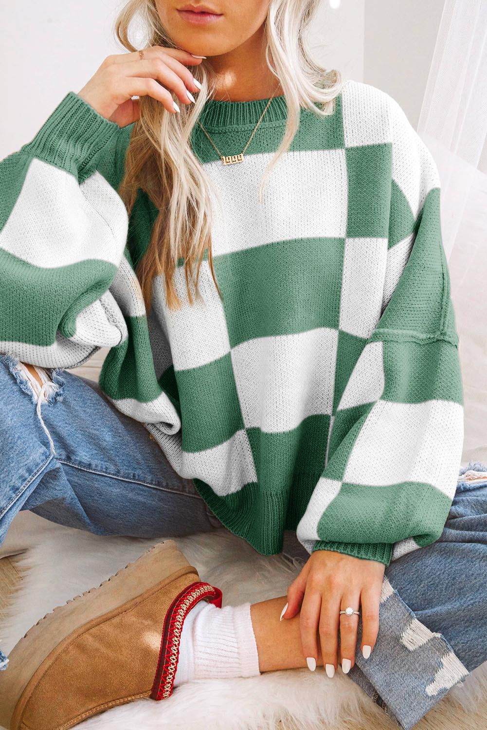 Person wearing a green and white checkered sweater with jeans and brown boots.