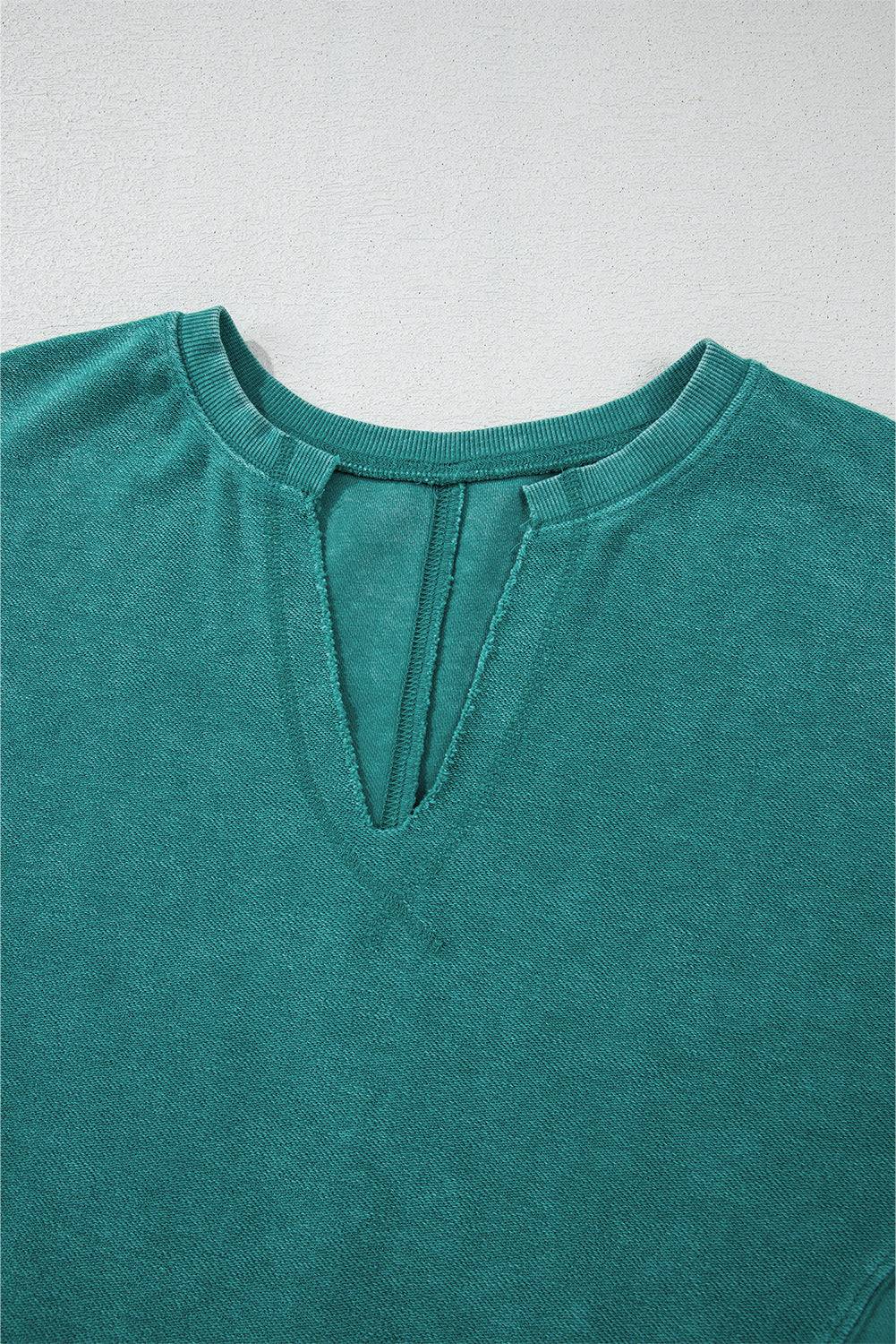 Close-up of a teal shirt with a V-neck on a light gray background