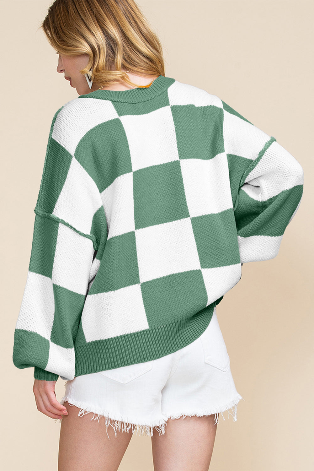 Person wearing a green and white checkered sweater on a beige background