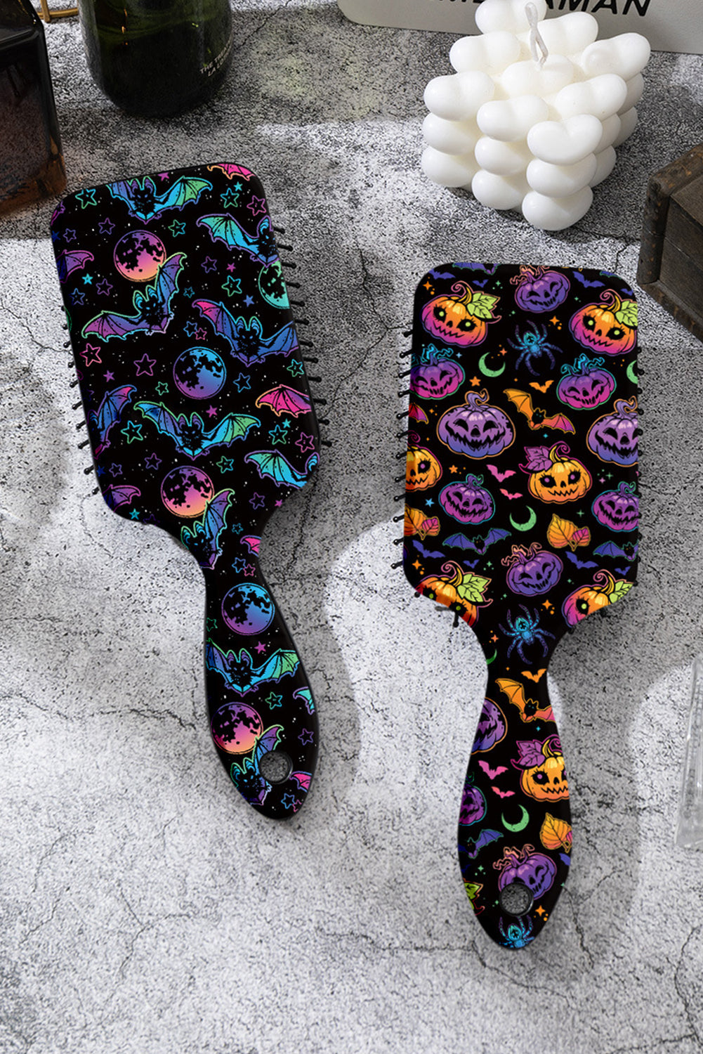Two hairbrushes with Halloween-themed designs on a textured surface.