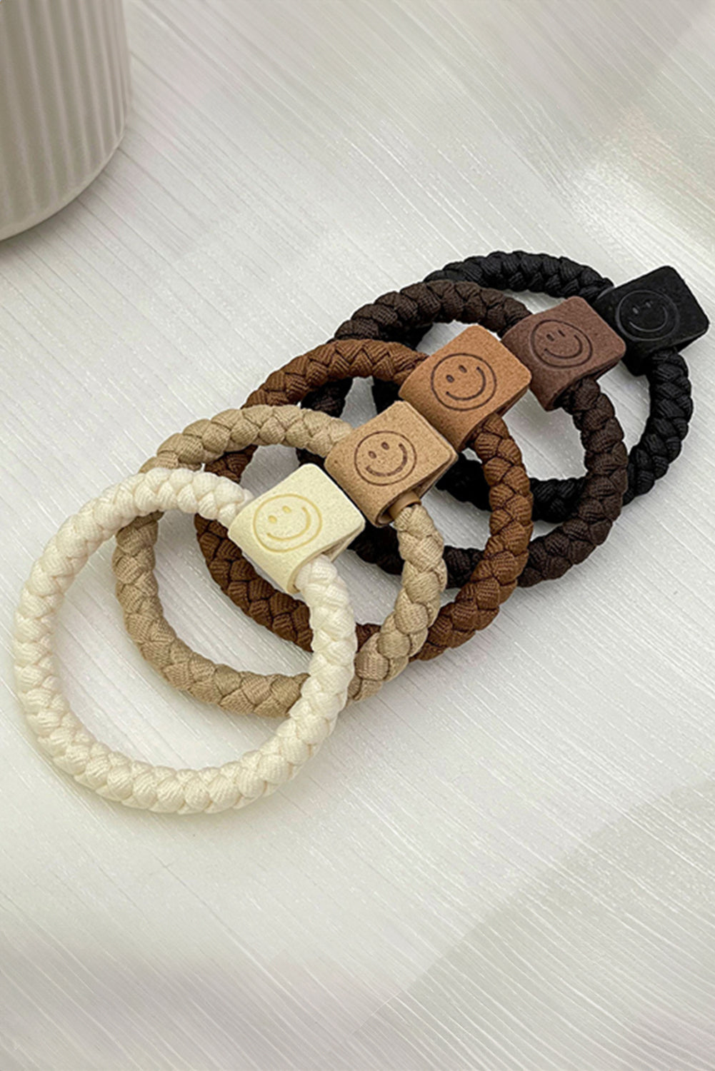 Set of braided hair ties with smiley face designs on a light surface