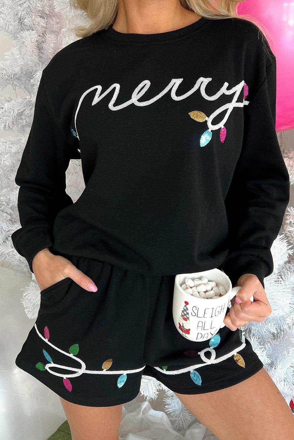 Person wearing a black outfit with 'merry' and light bulb designs, holding a mug.