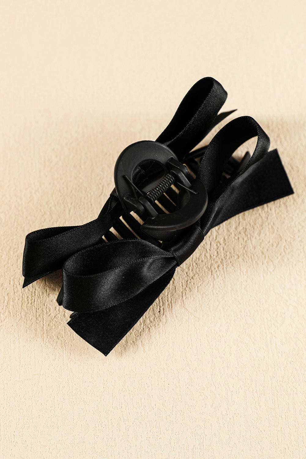 Black bow hair clip on a beige background