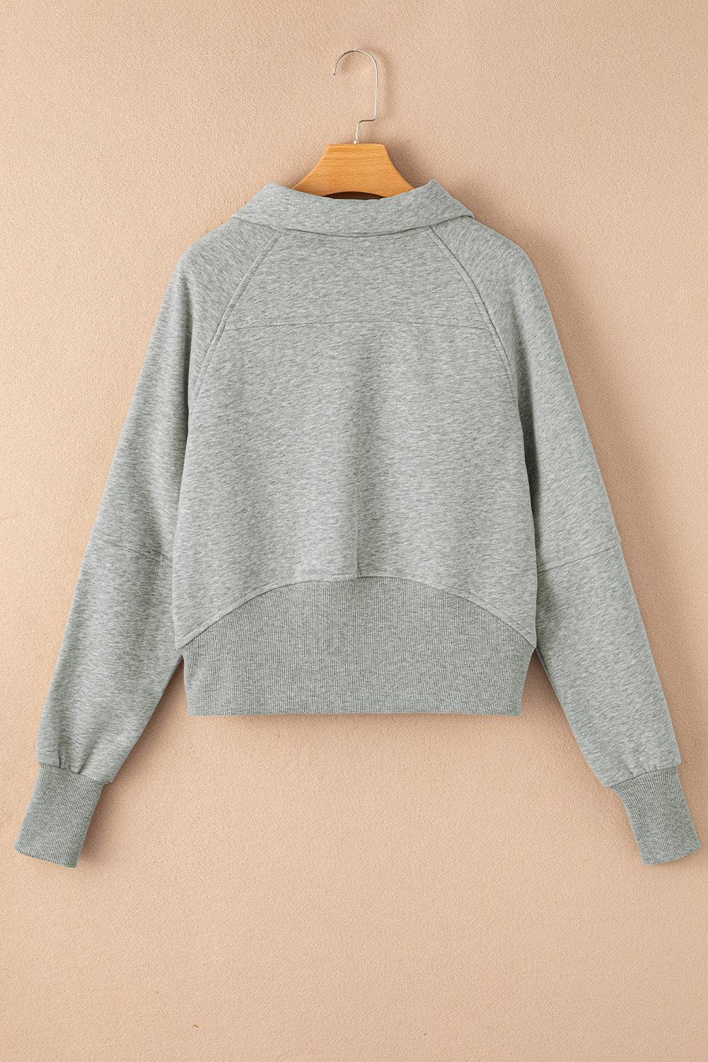 Gray sweatshirt on a wooden hanger against a beige background