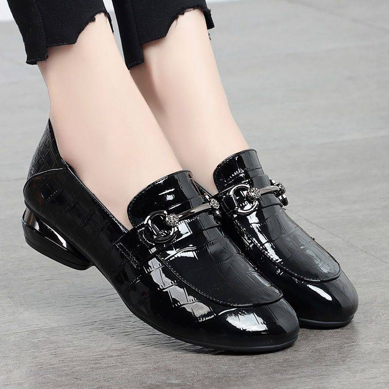 Black patent leather shoes with a buckle on a gray background