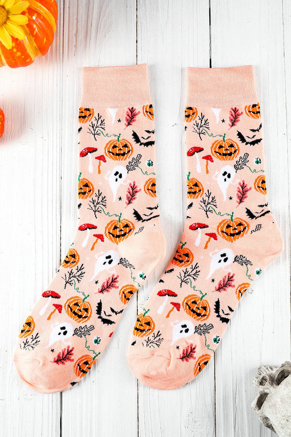 Halloween-themed socks with pumpkins, ghosts, and leaves on a light wooden background.