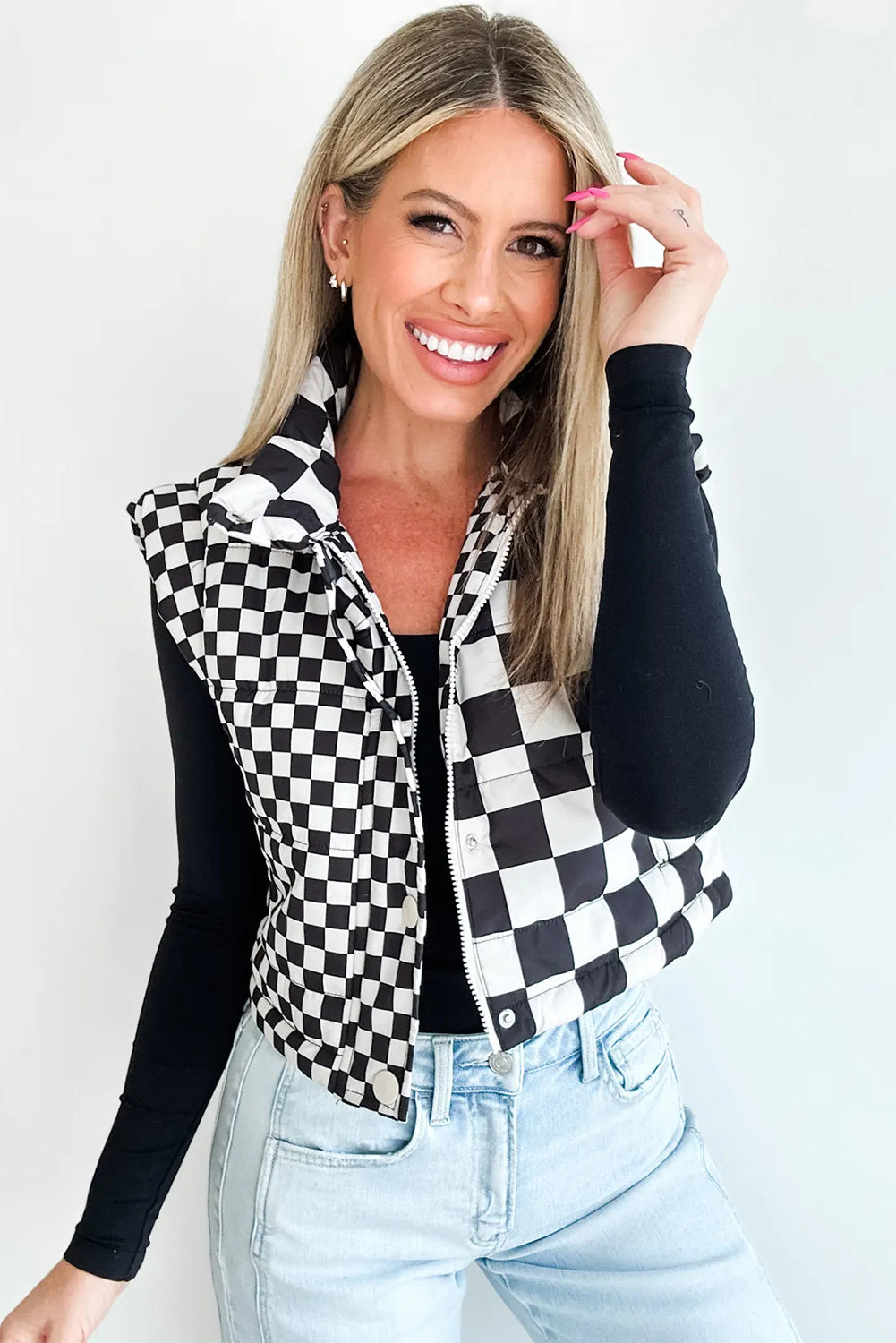 Woman wearing a black and white checkered vest against a plain background