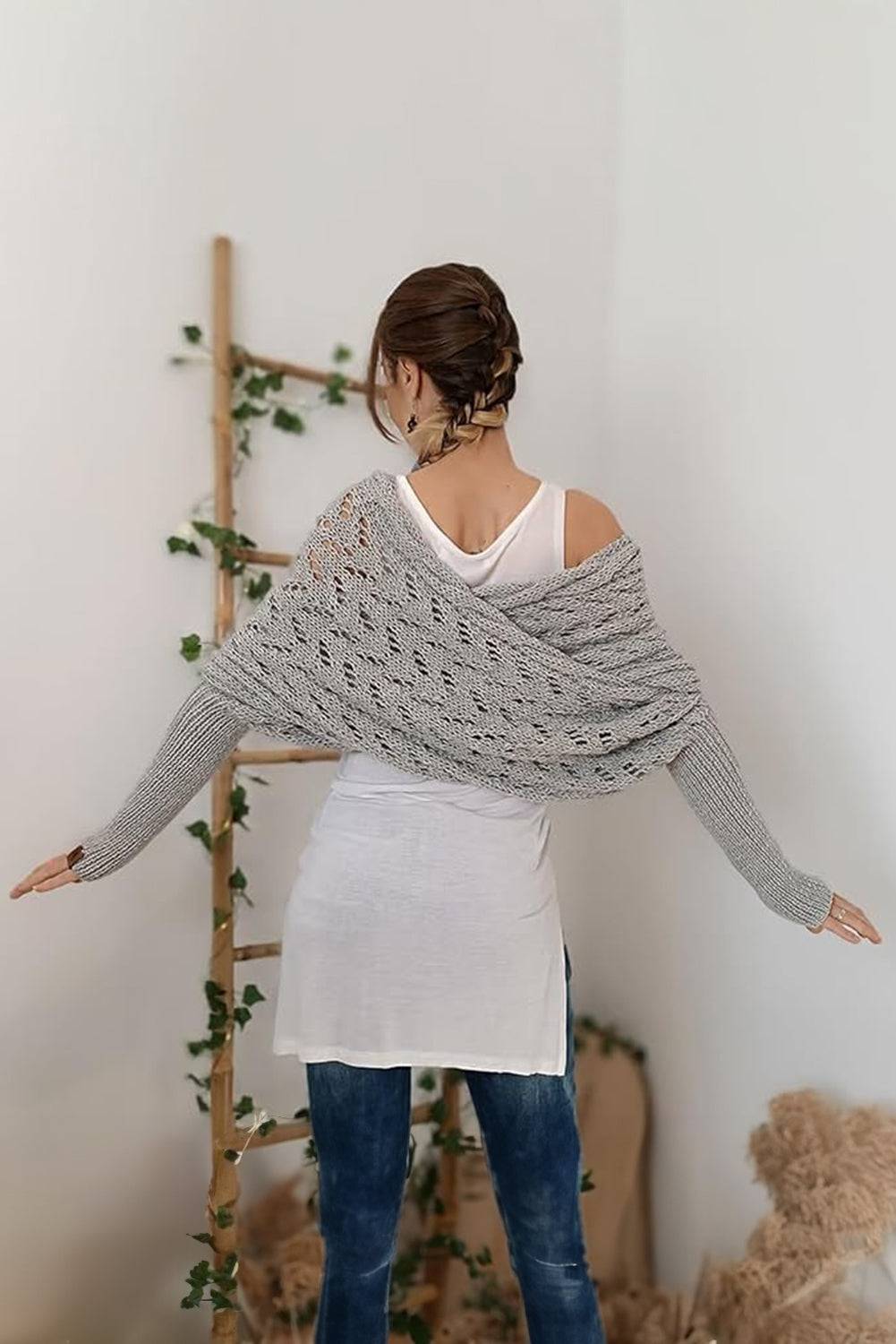 Woman wearing a gray knitted shawl over her shoulders in a minimalistic room.