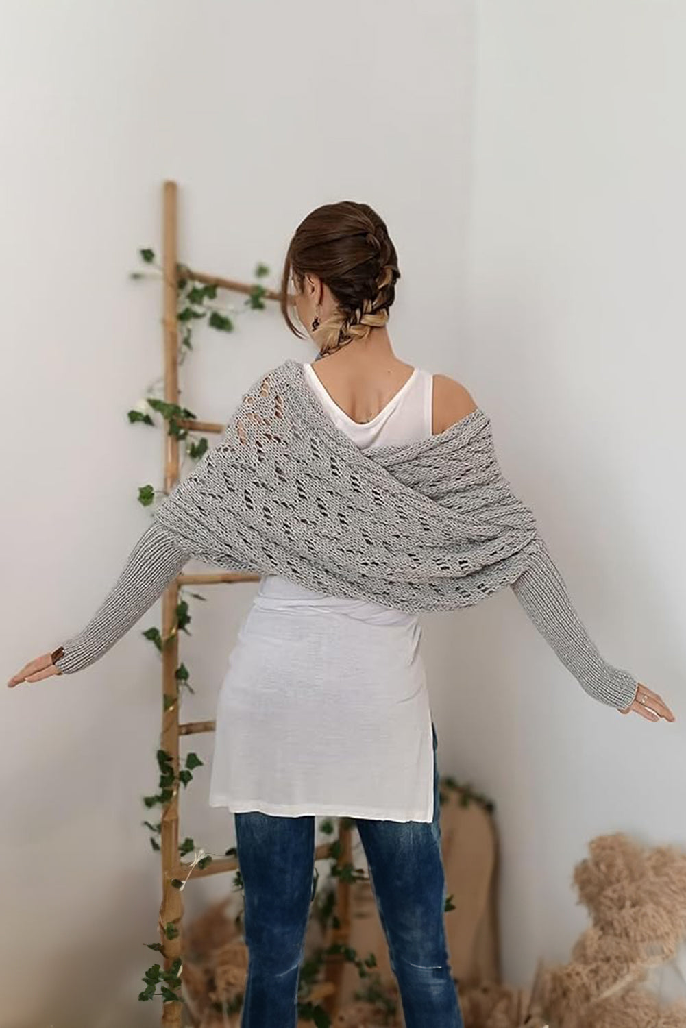 Woman wearing a gray knitted shawl over her shoulders in a minimalistic room.