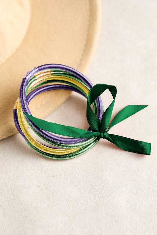 Set of colorful ribbons tied together with a green ribbon on a beige background