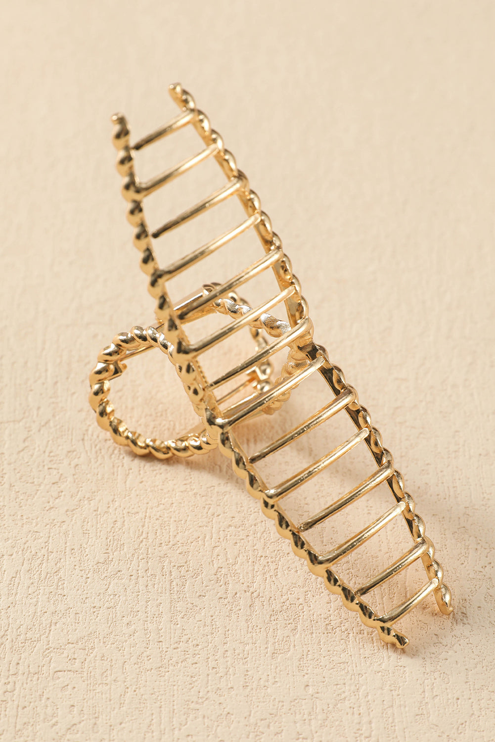 Gold ladder-shaped brooch on a beige background