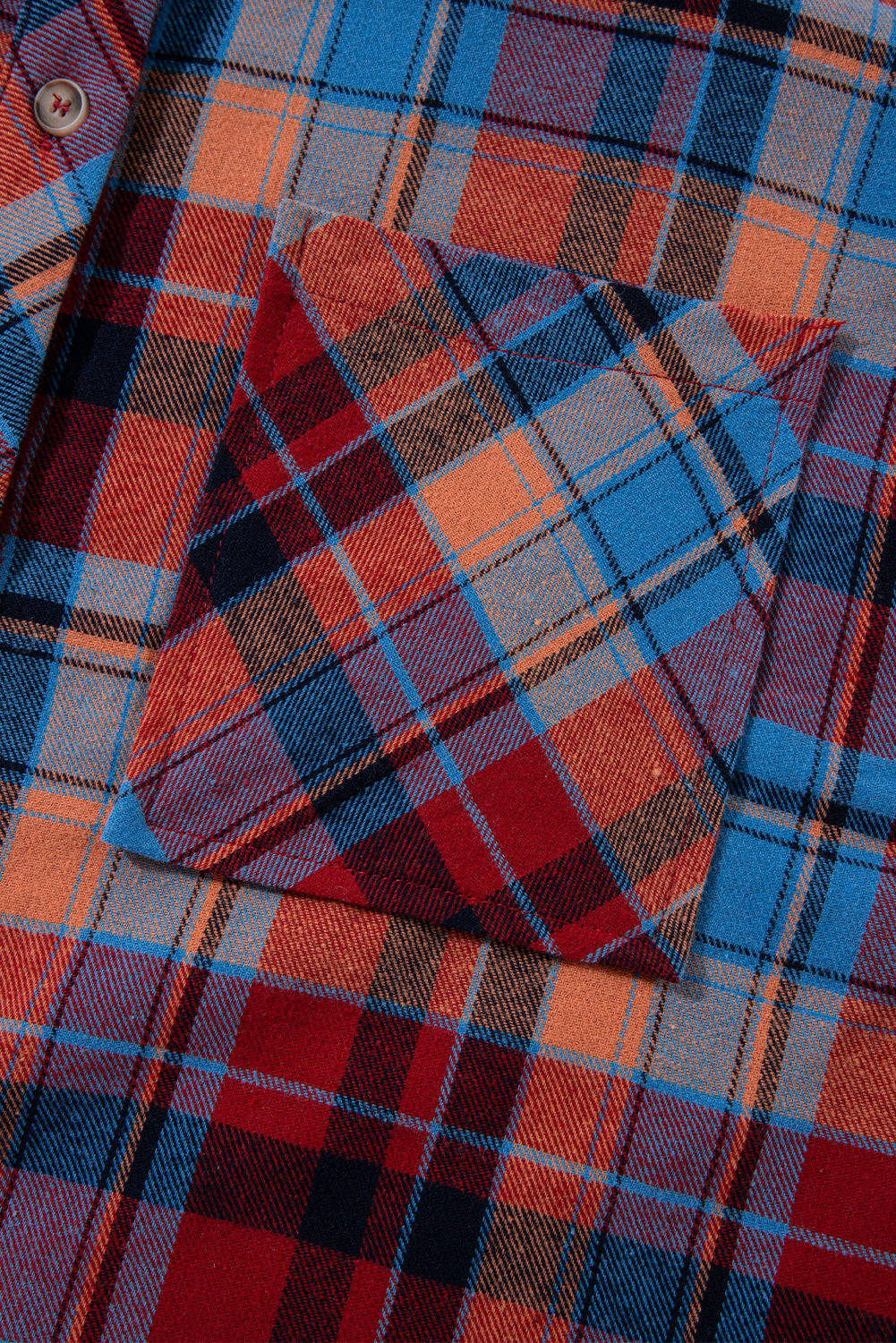Close-up of a plaid fabric with red, blue, and orange colors.