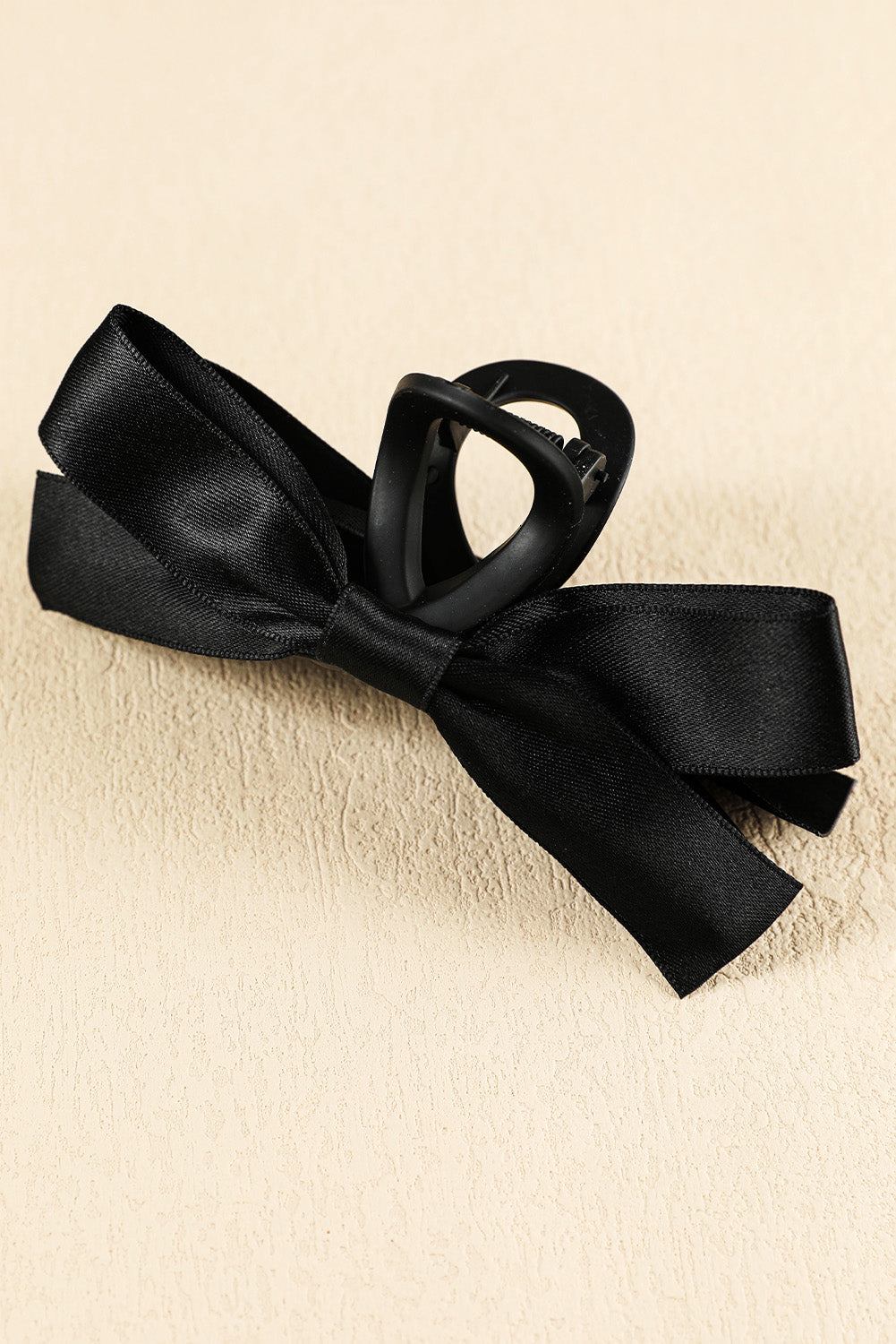 Black satin ribbon bow on a beige background