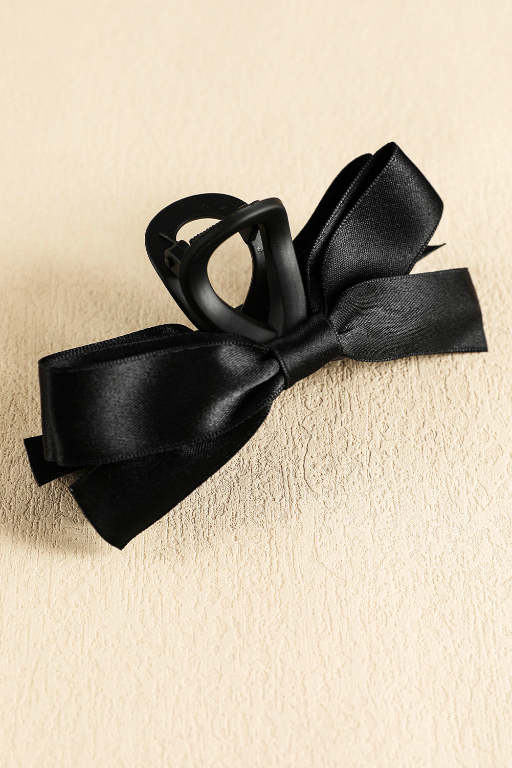 Black bow hair clip on a beige background