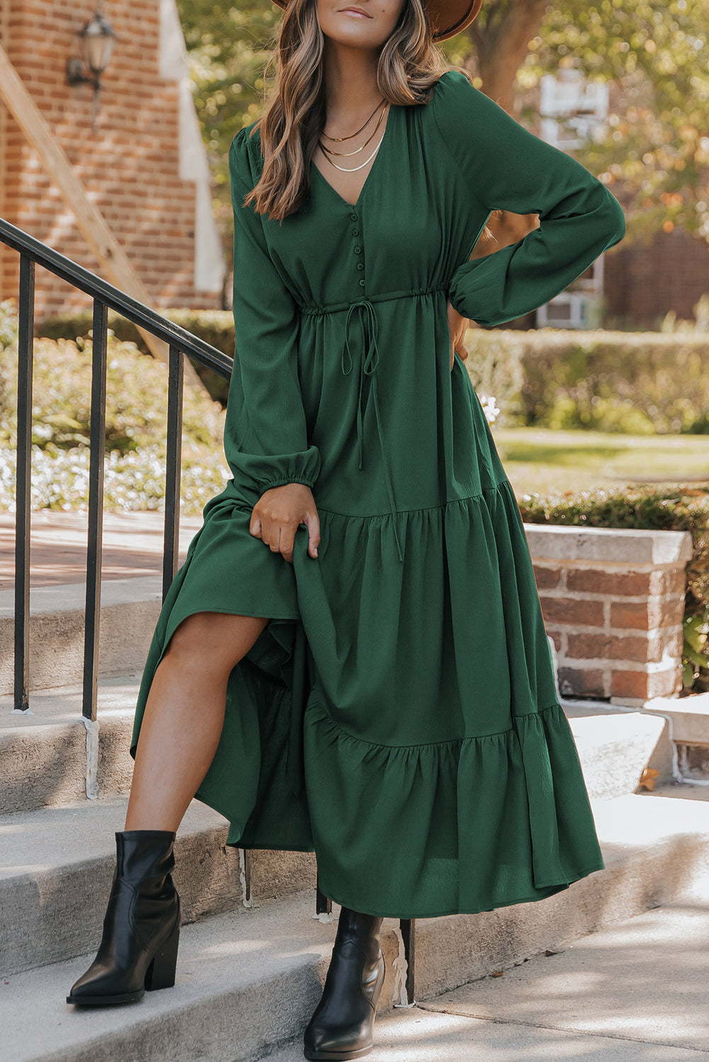 Woman in a green dress standing on steps outdoors