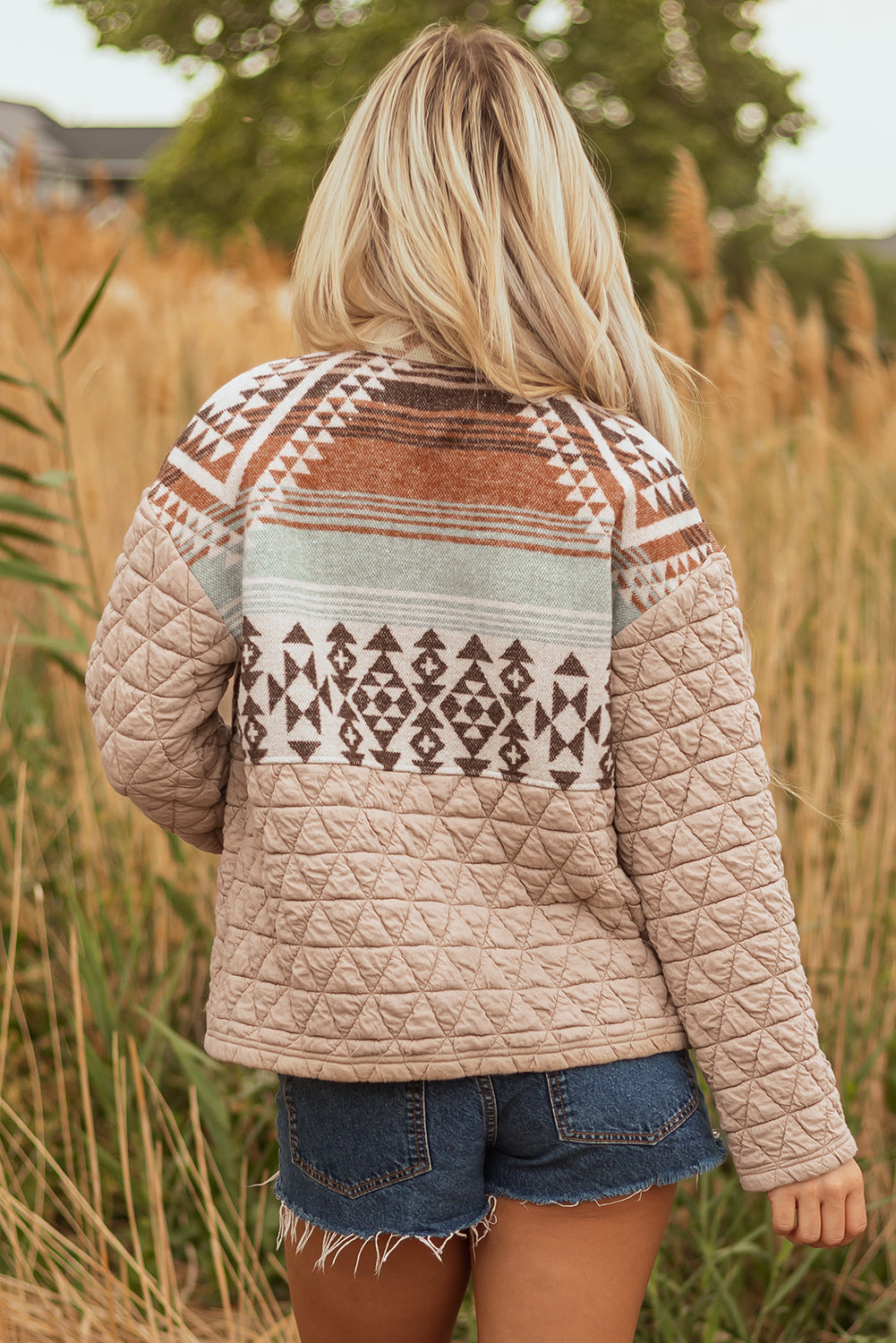 Person wearing a patterned quilted jacket in a natural setting