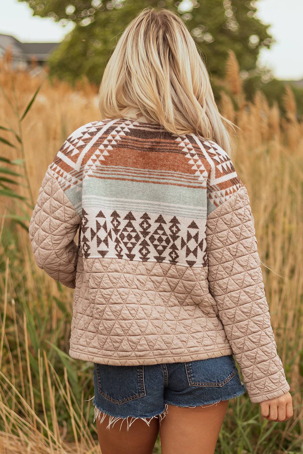 Person wearing a patterned quilted jacket in a natural setting
