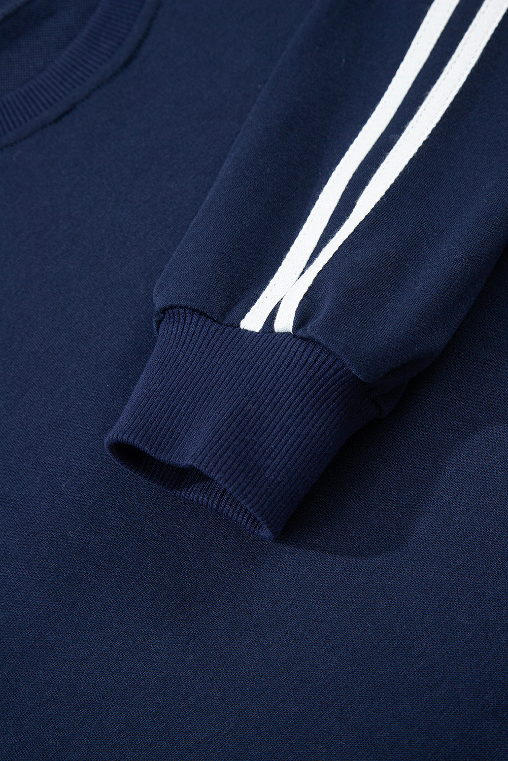 Navy blue sweatshirt with white stripes on the sleeve against a matching background