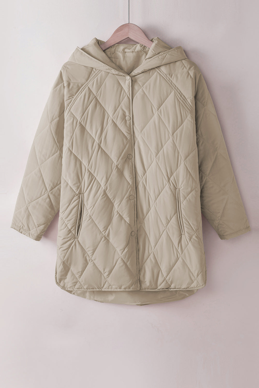 Beige quilted jacket on a pink hanger against a light pink background