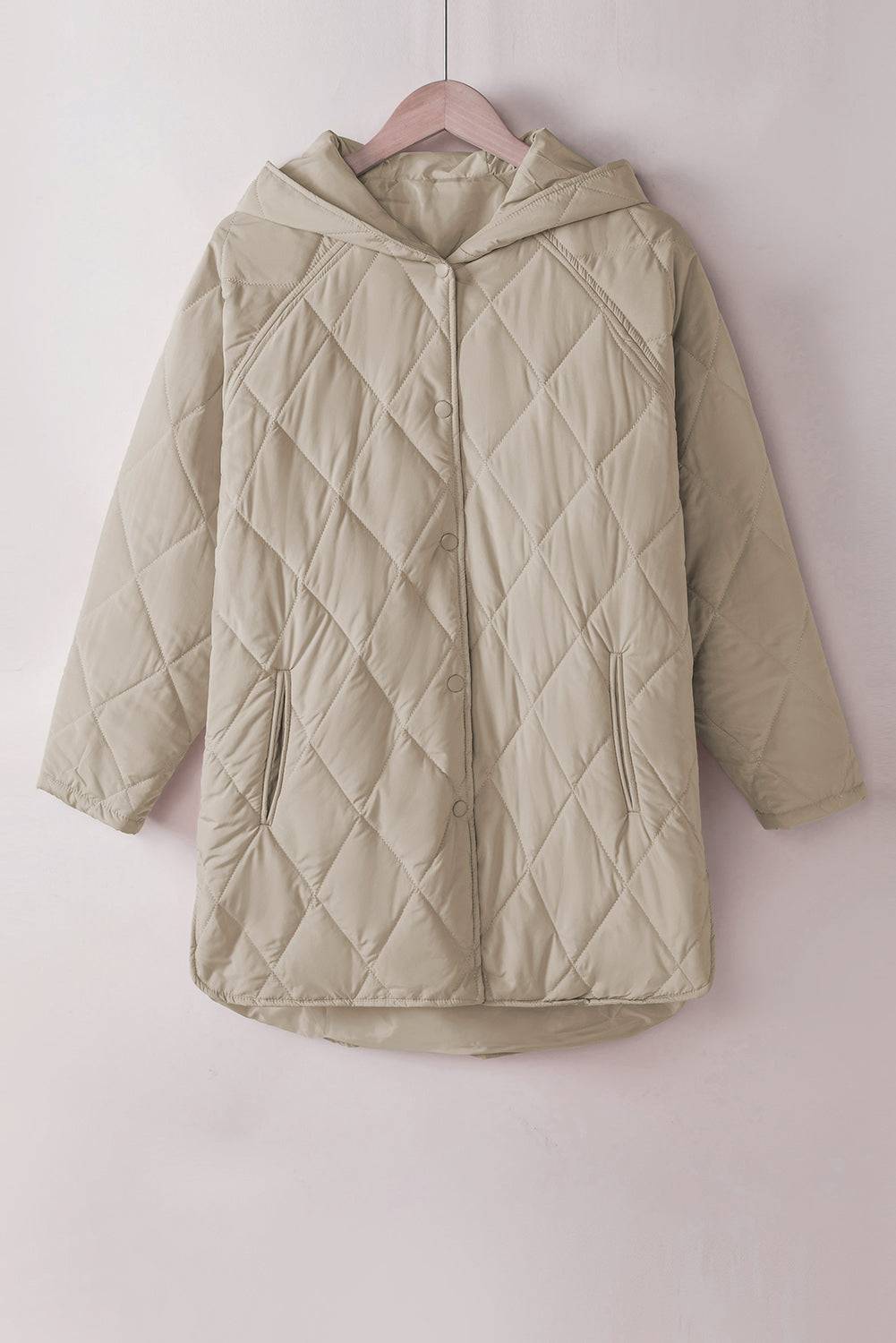 Beige quilted jacket on a pink hanger against a light pink background
