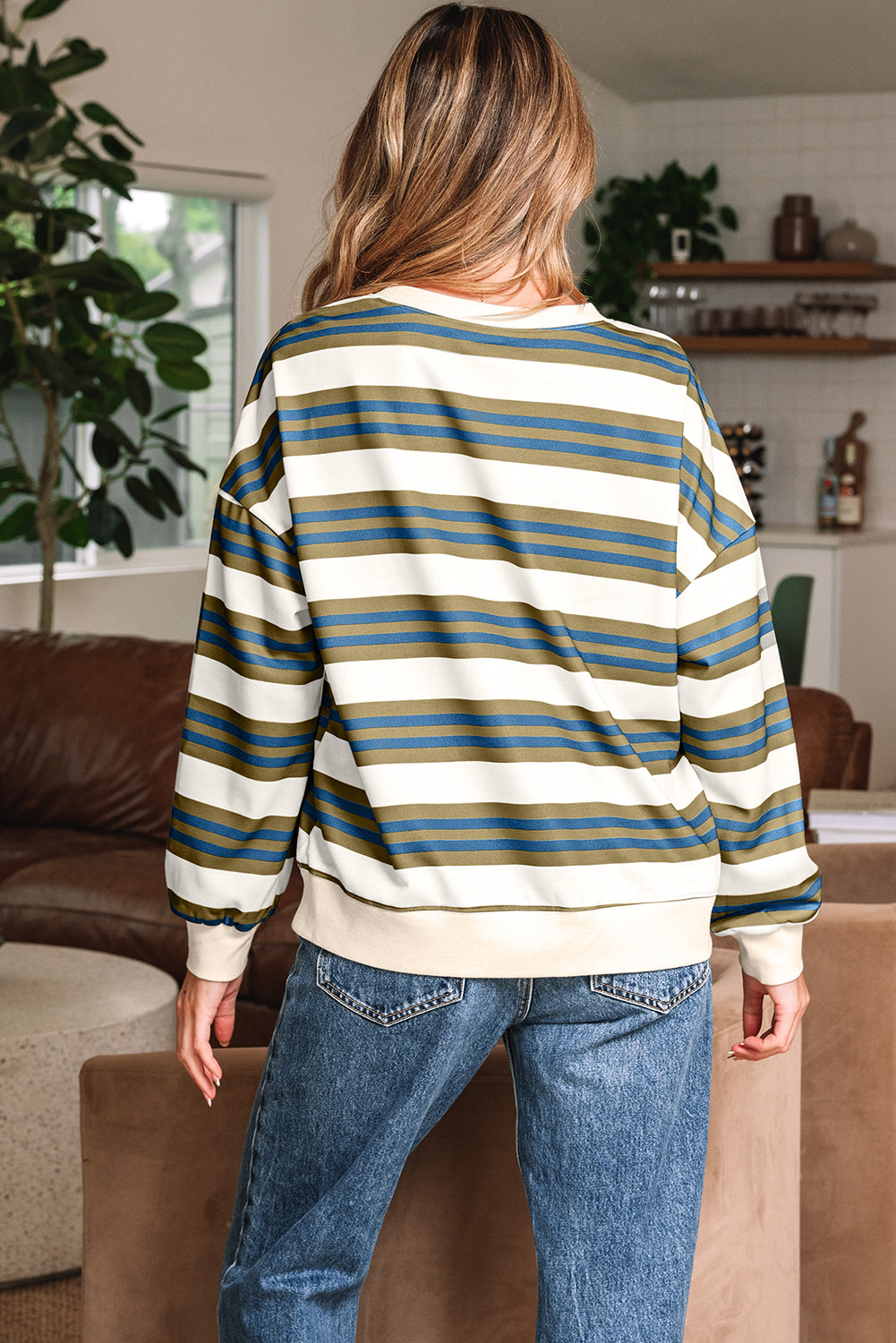 Person wearing a striped sweater and jeans in a living room setting