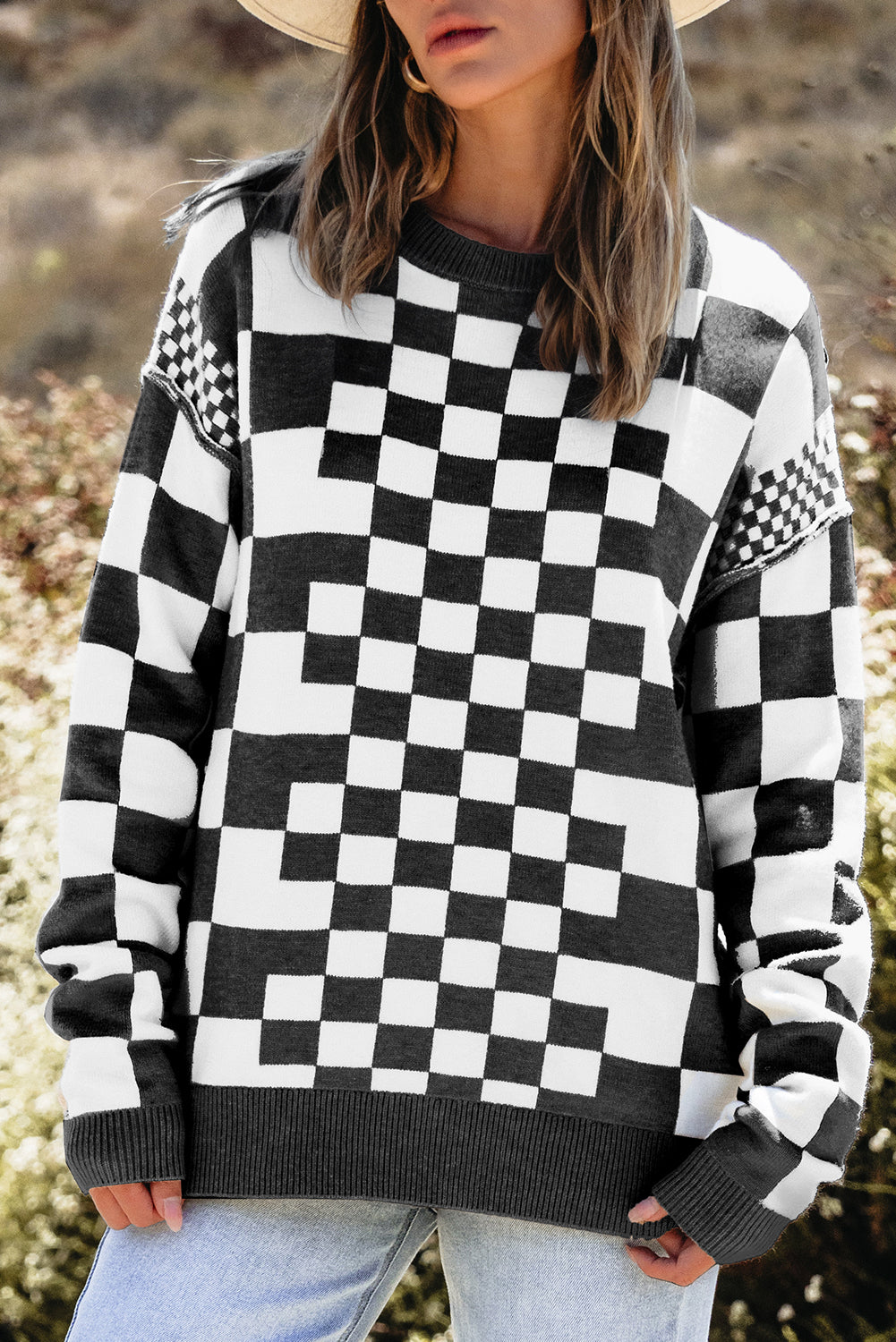 Person wearing a black and white checkered sweater with a blurred natural background