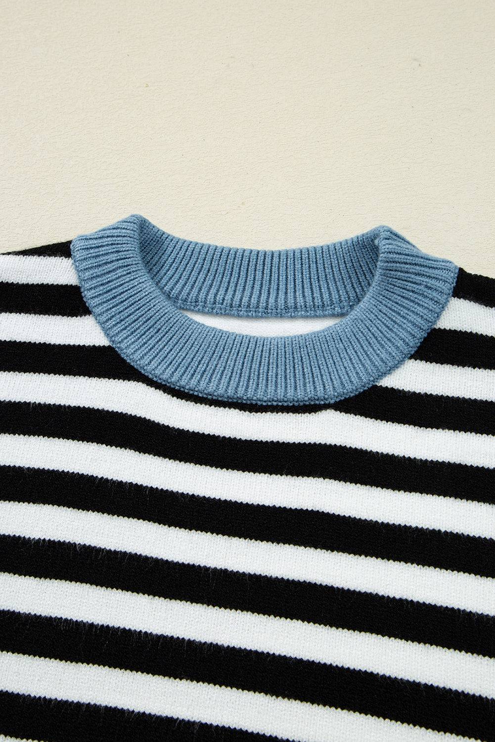 Close-up of a black and white striped sweater with a blue ribbed collar on a beige background