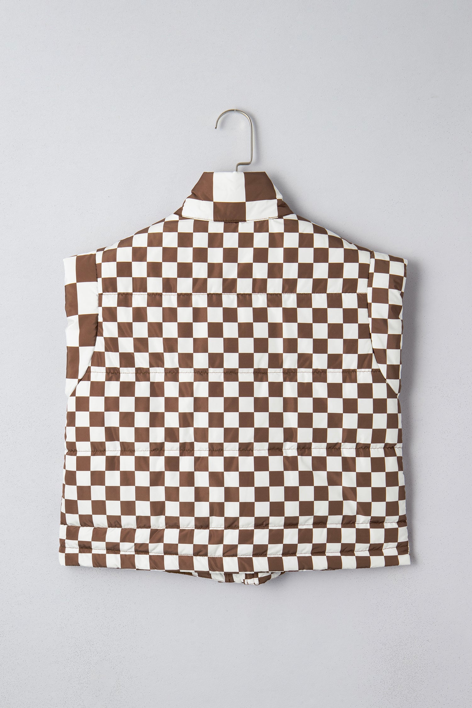 Brown and white checkered shirt on a hanger against a gray background