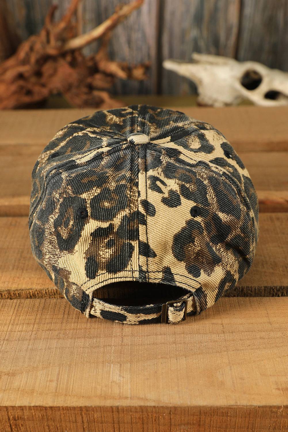 Leopard print cap on a wooden surface with driftwood and a skull in the background