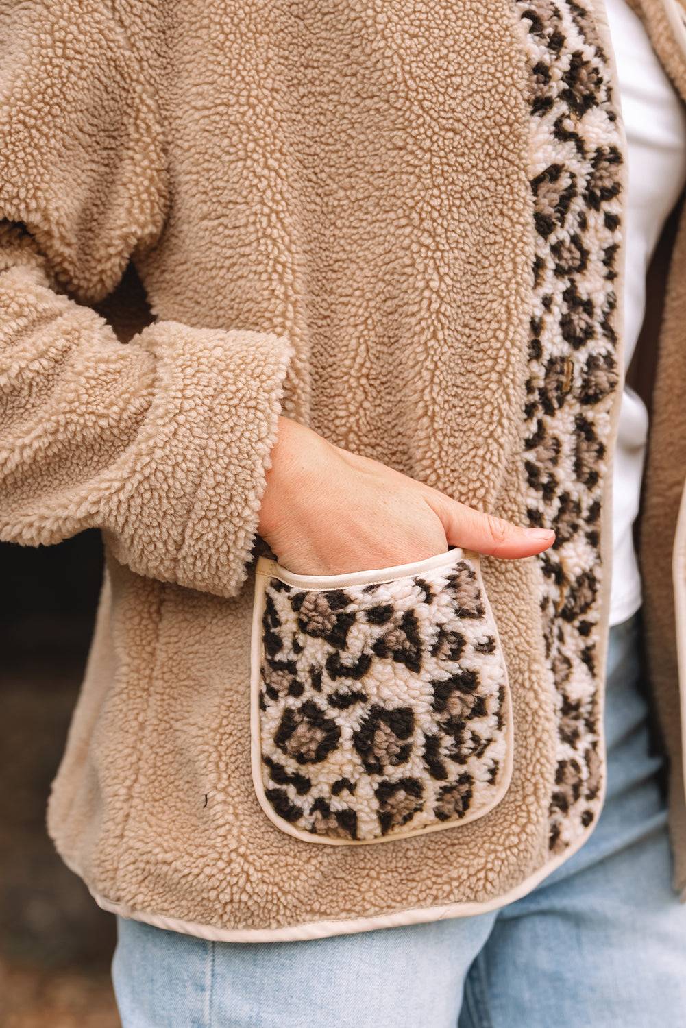 Close-up of a beige fleece jacket with leopard print pocket and trim.