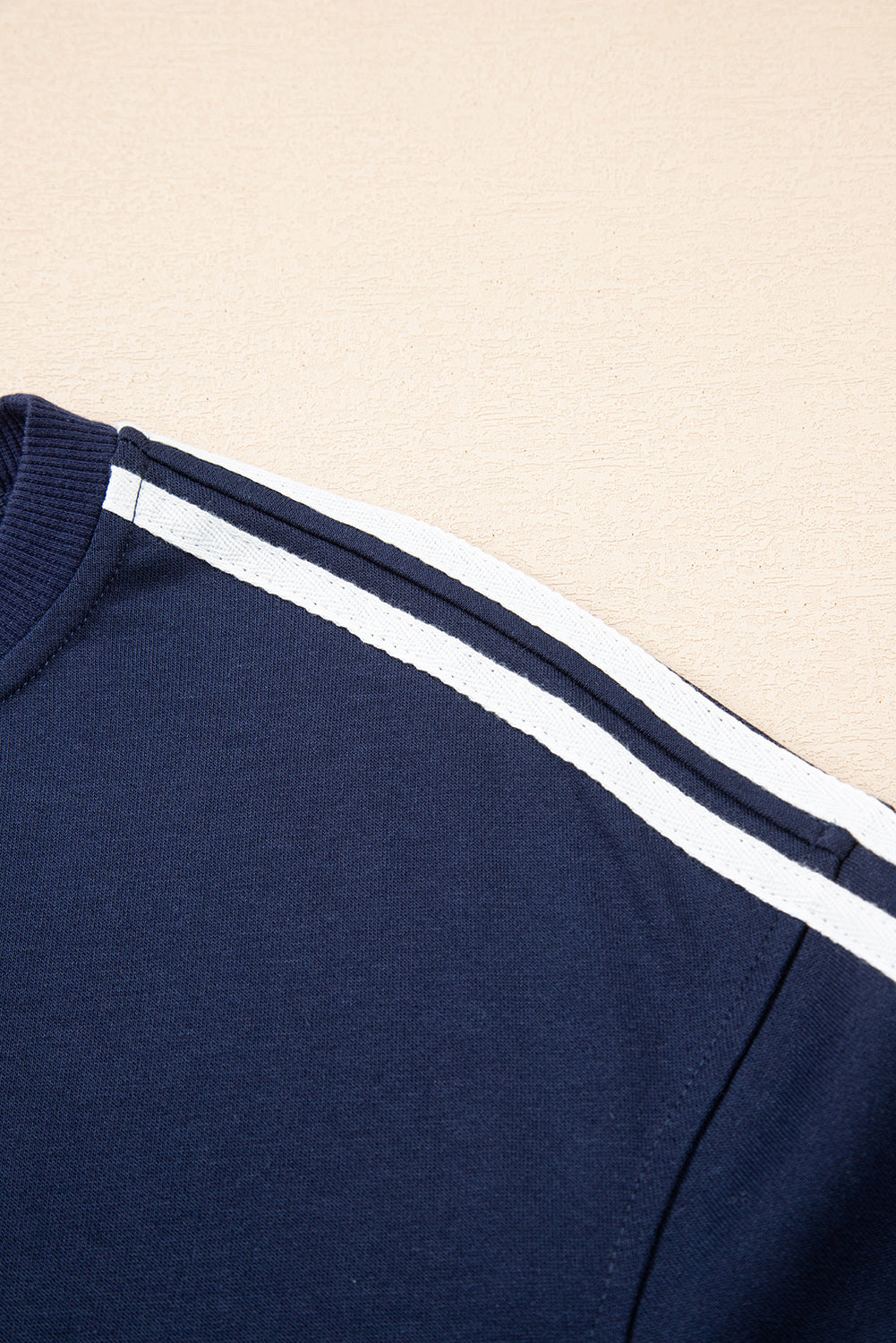 Navy blue sweatshirt with white stripes on a beige background