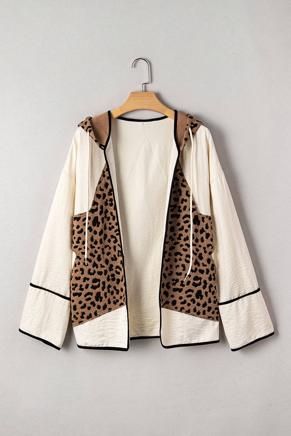Leopard print jacket with cream and black accents on a wooden hanger against a gray background