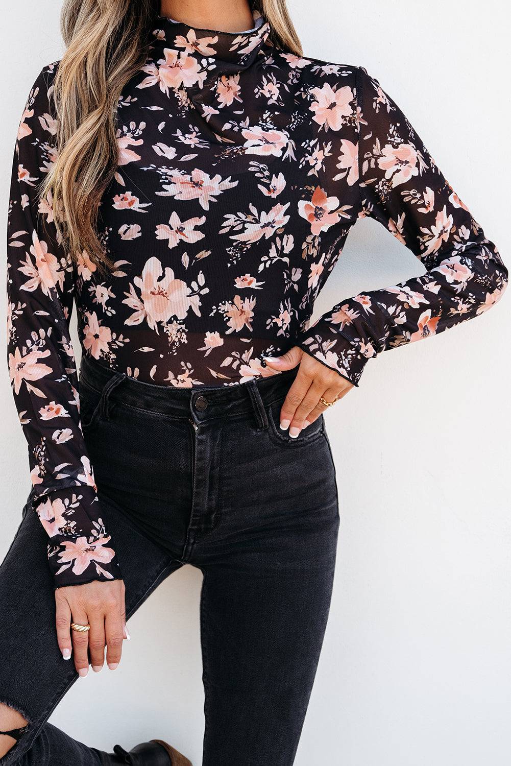 Person wearing a black floral long-sleeve top and black jeans 