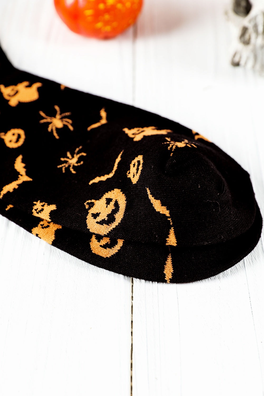 Black sock with Halloween-themed orange patterns on a white background